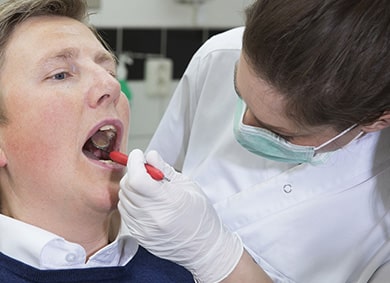 Dentist in Toronto uses mirror to examine patient's dental bridges