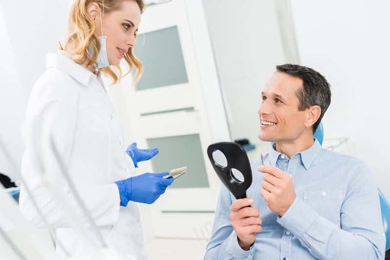 Cordial dentist advising patient on proper dental implant care